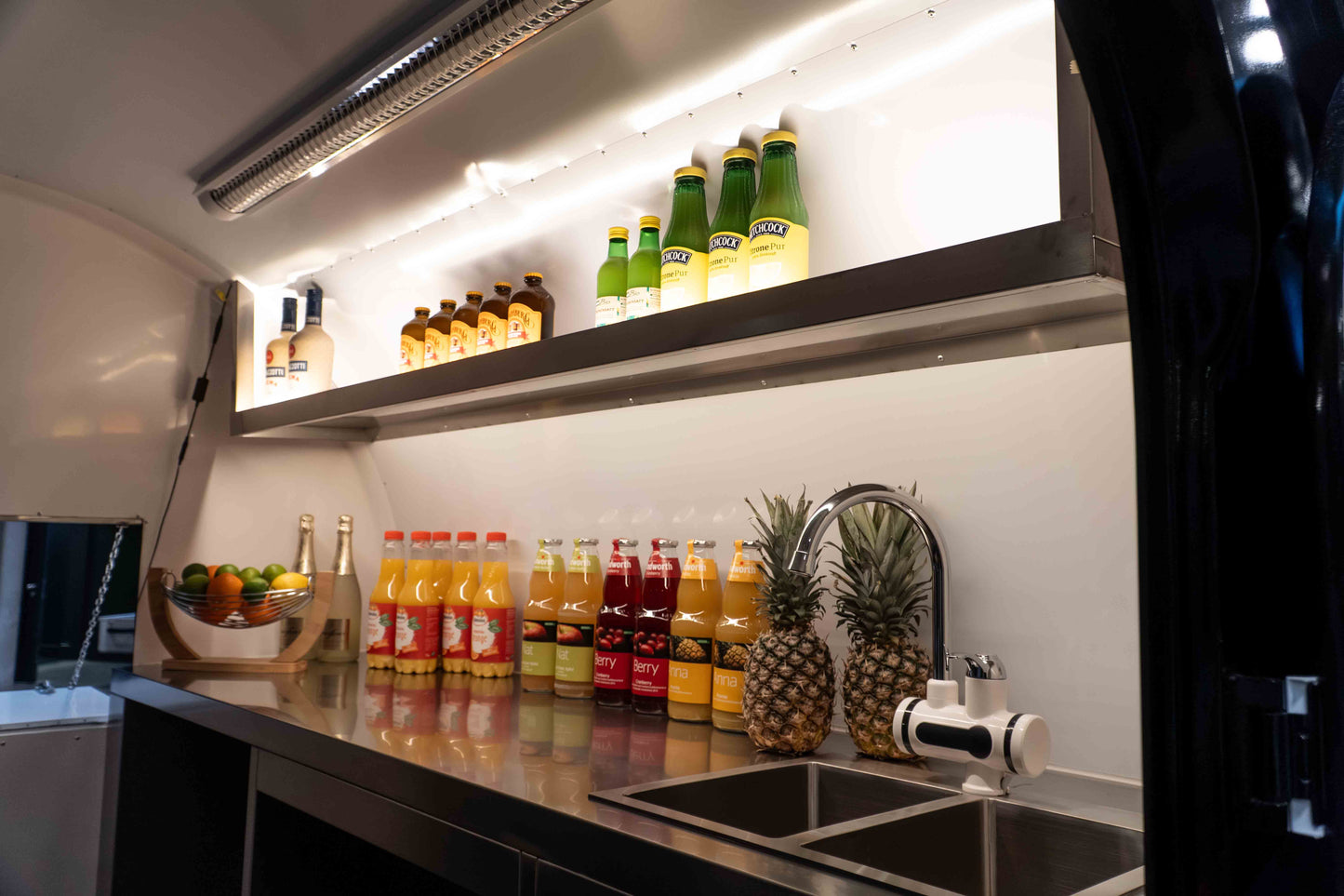 Die Arbeitsfläche eines Verkaufsanhängers mit einigen Flaschen und dem Spülbecken auf der rechten Seite