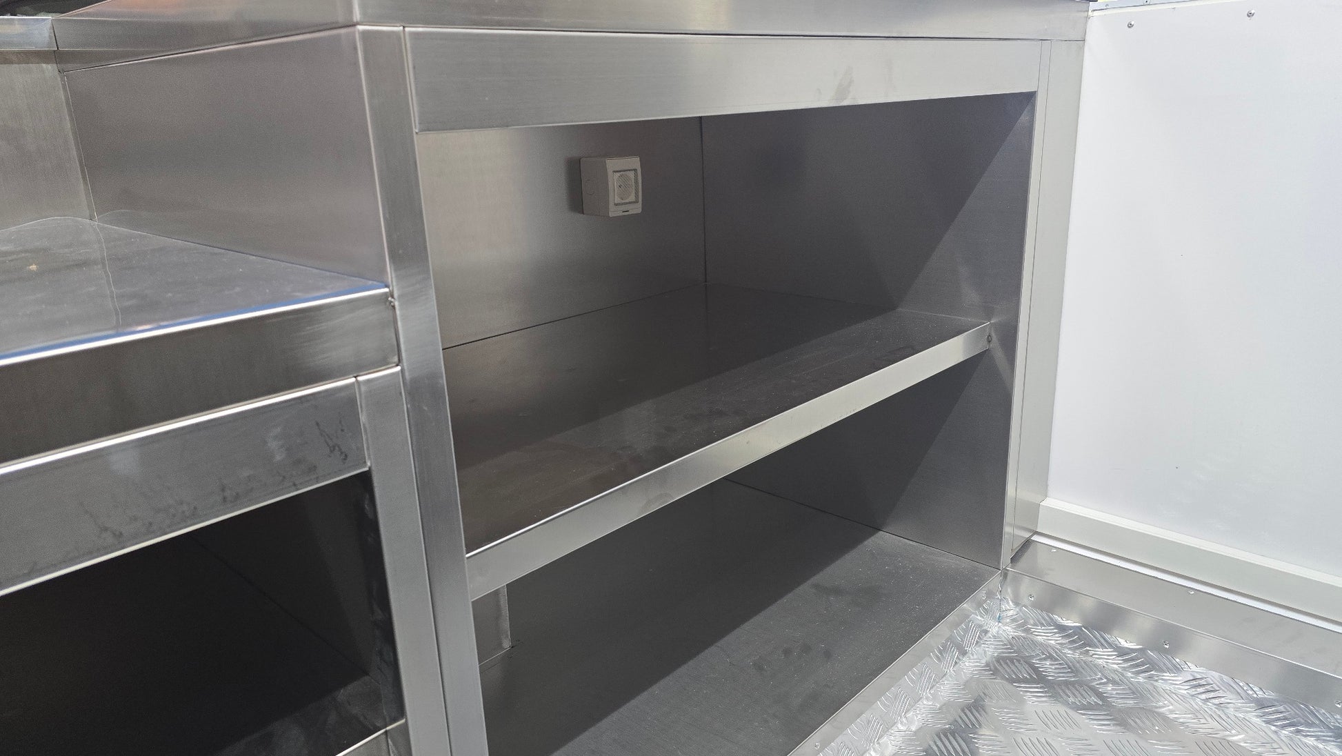 Innenansicht eines Foodtrailers mit Einrichtung, Arbeitsflächen und Schränken mit Verstaumöglichkeiten.