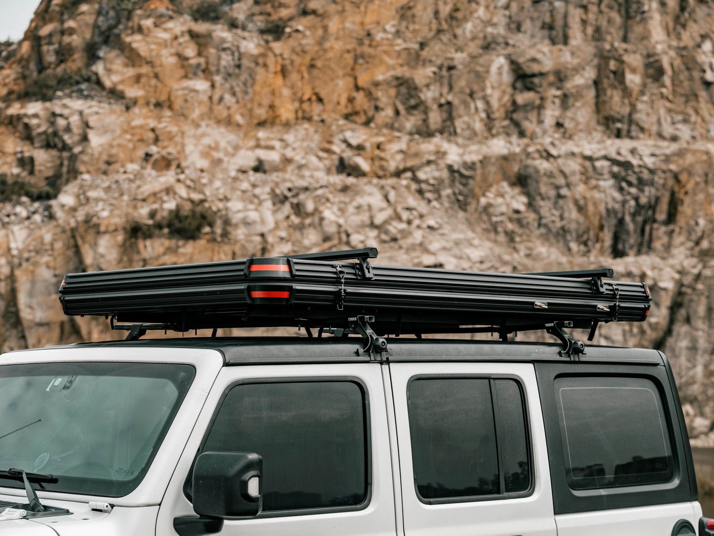Hartschalendachzelt auf Jeep vor Felzwand. 