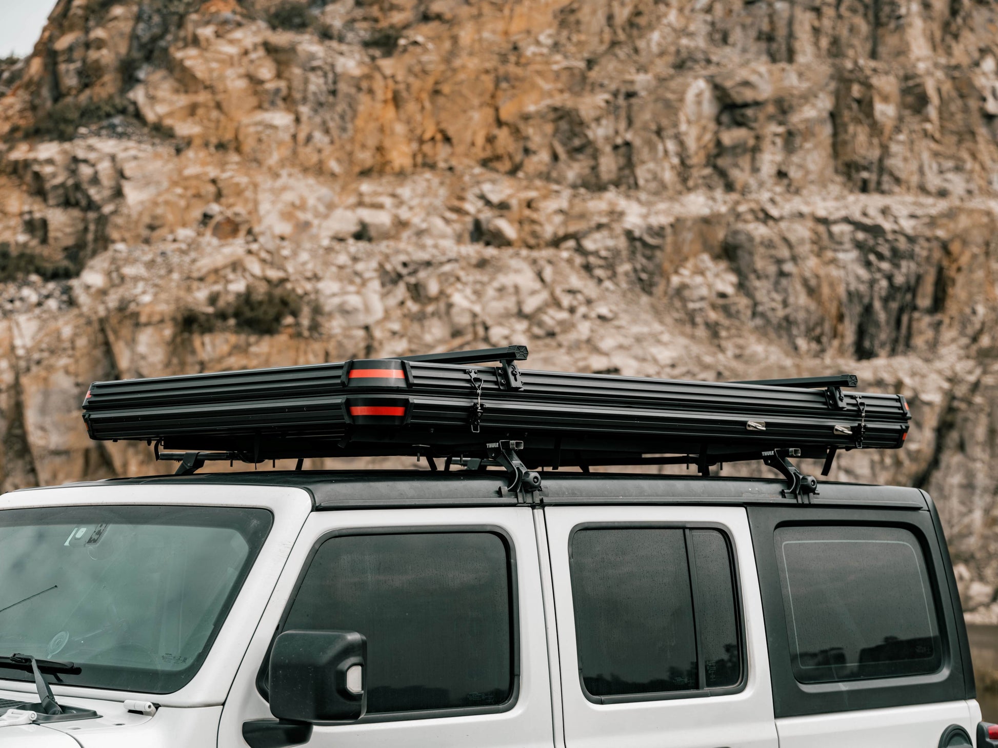 Hartschalendachzelt auf Jeep vor Felzwand. 