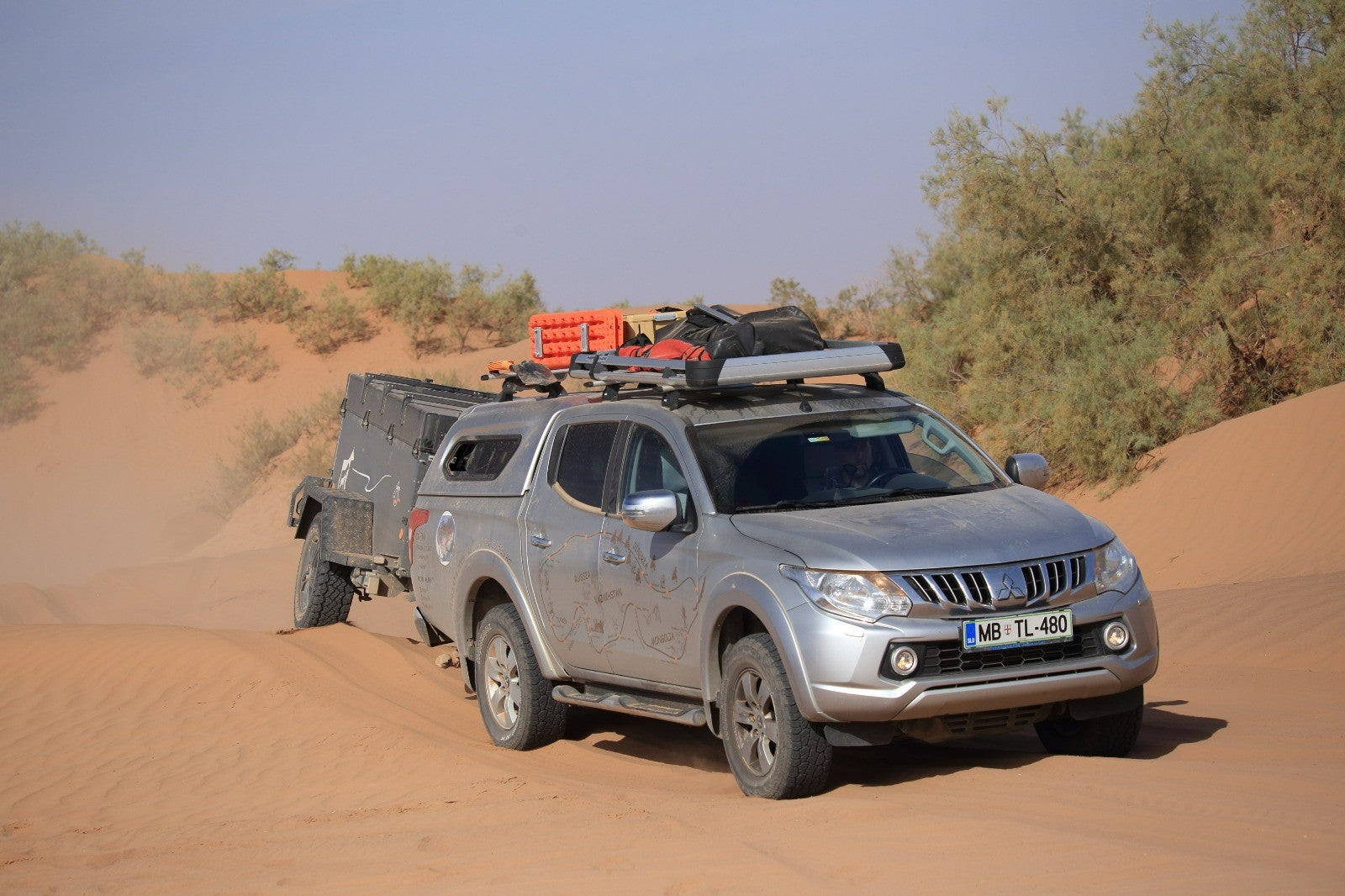 Offroad Anhänger, der von einem Geländewagen durch Sanddünen gezogen wird