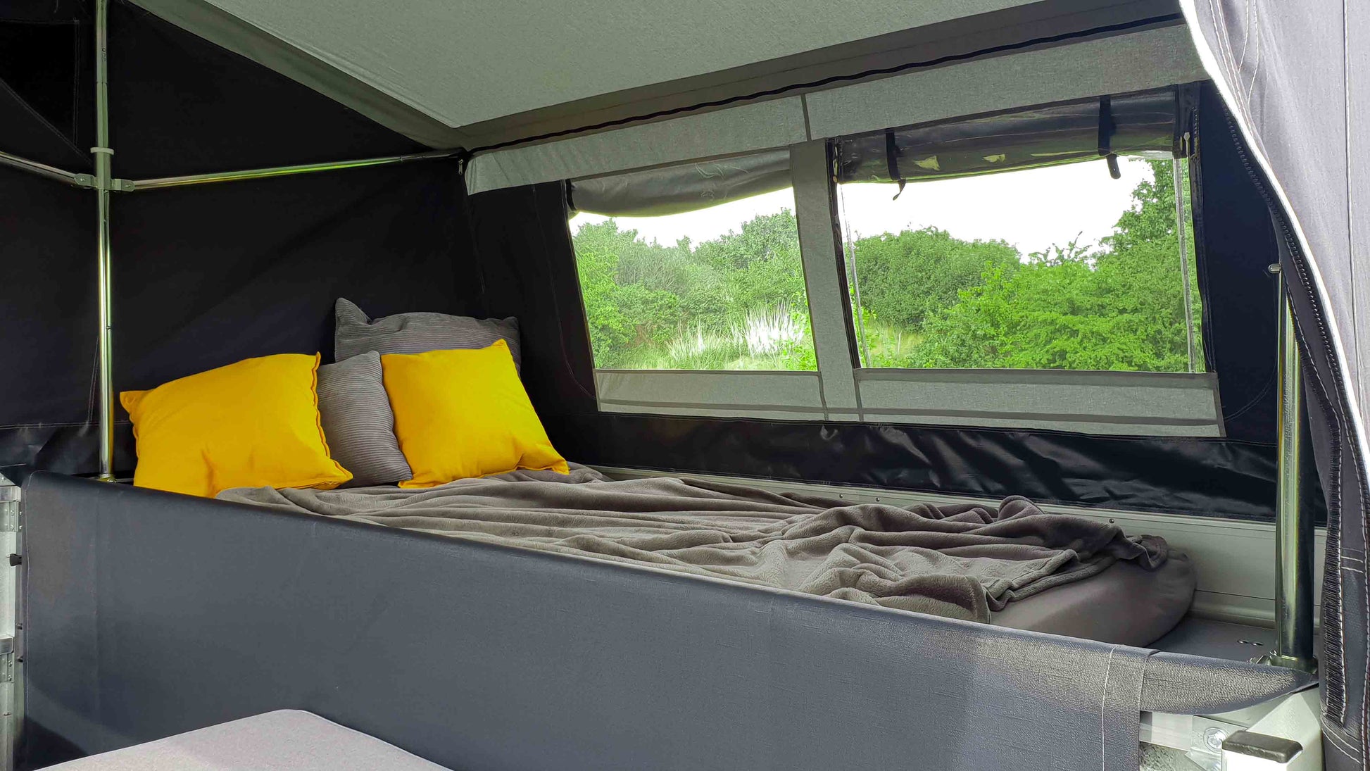 Innenansicht eines Klappcampers mit Blick auf die Matratze bzw. die Fenster mit Klarsichtfolie