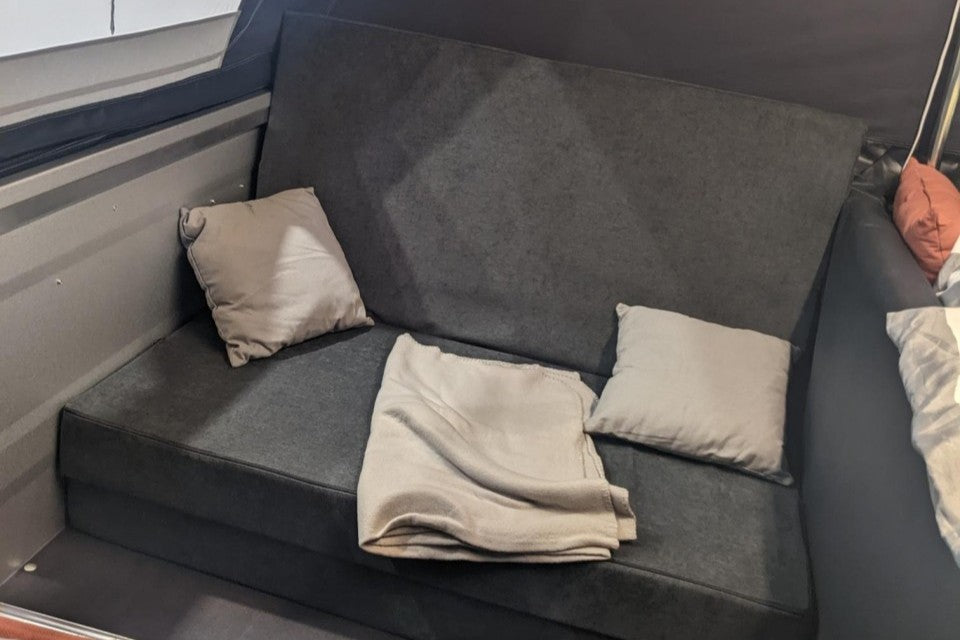 Eine Faltmatratze gebaut als Couch oder Sessel dekoriert mit Kissen und Decke