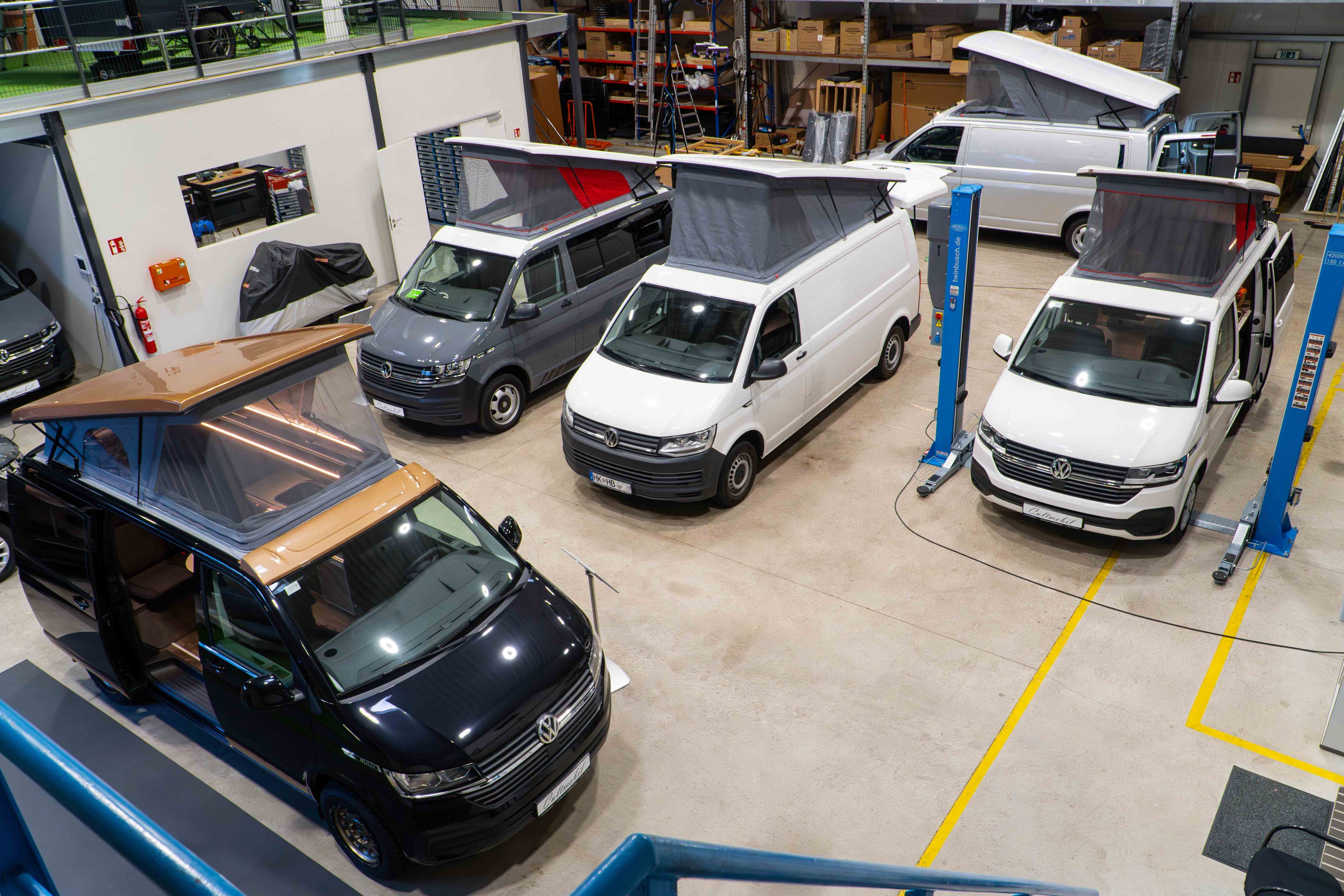Ein Ausstellungsraum von oben n einer Halle mit Blick auf die Aufstelldächer von VW Camper Vans