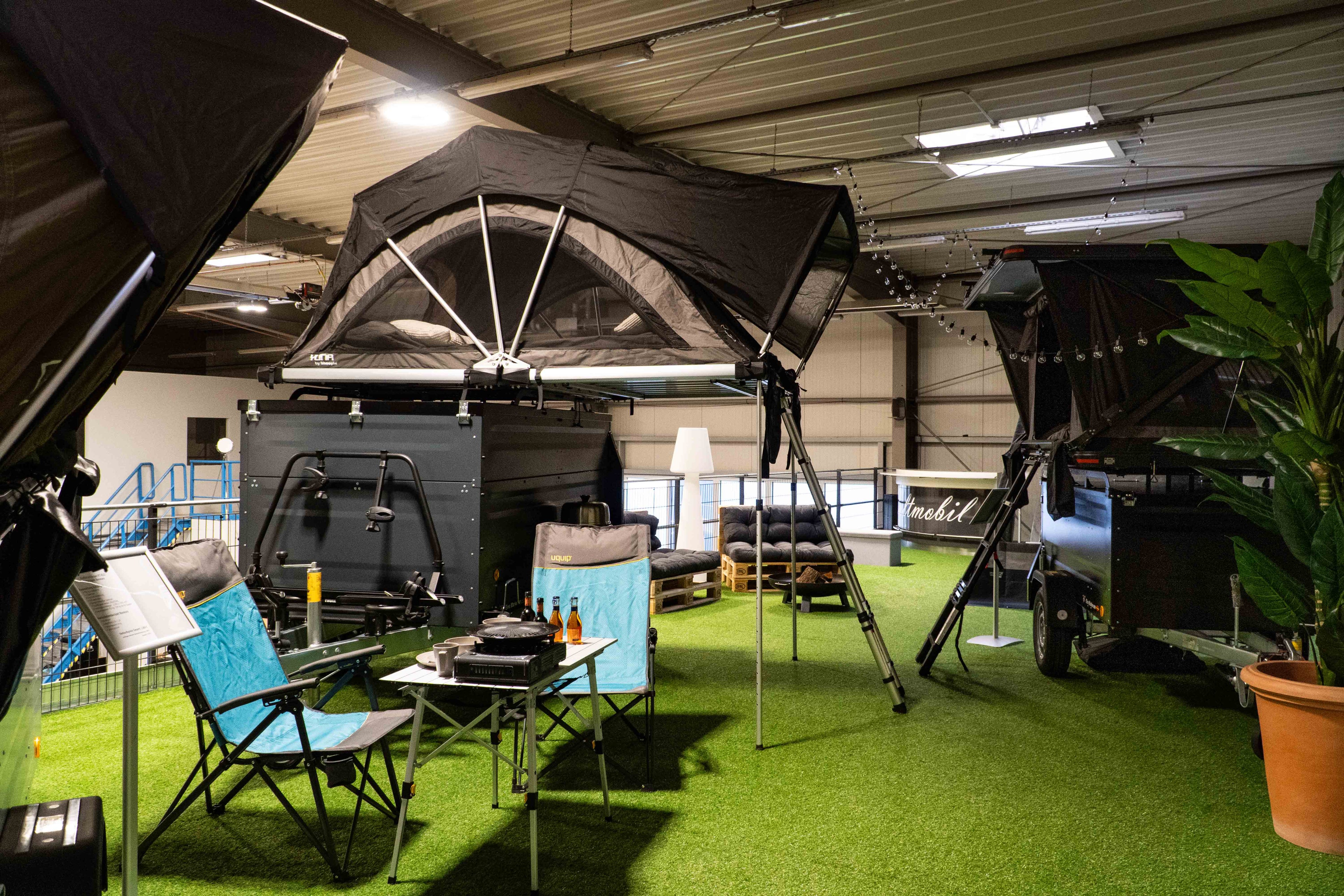 Ein Ausstellungsraum mit verschiedenen Campingartikel wie Dachzelten