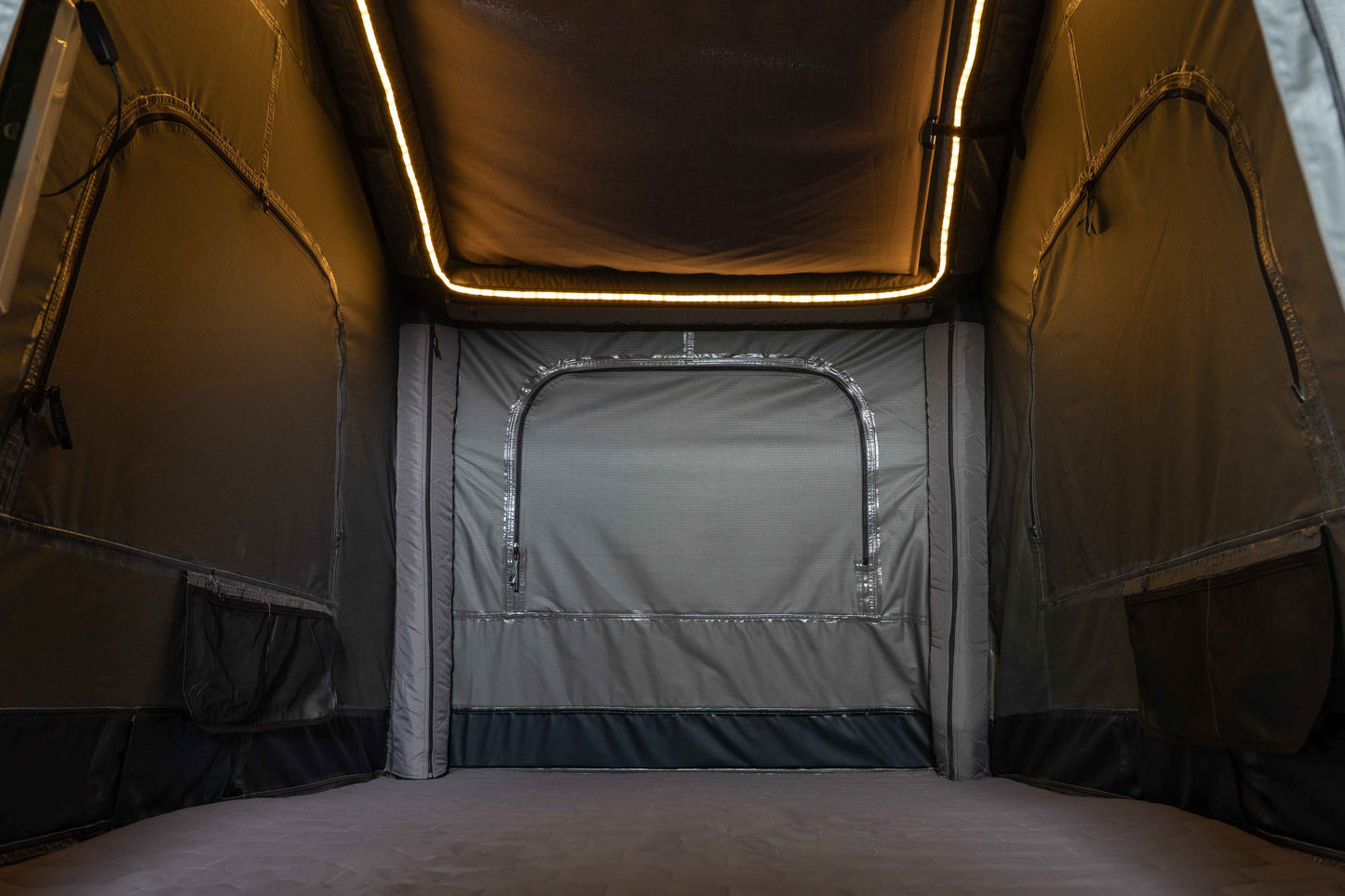 Dachzelt von innen mit umlaufender Beleuchtung mit Blick auf die Matratze, Seiten und den Himmel. 