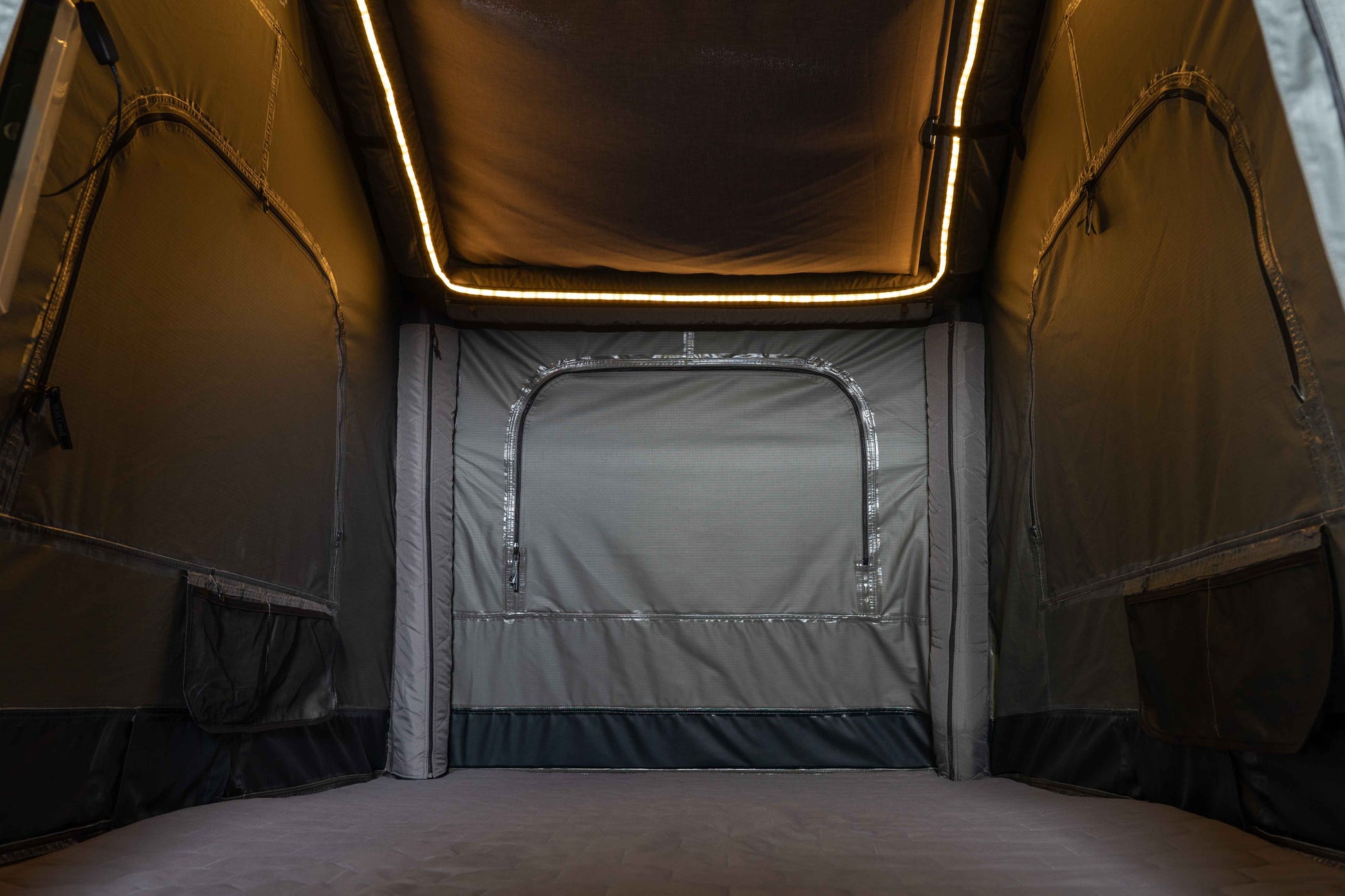 Dachzelt von innen mit umlaufender Beleuchtung mit Blick auf die Matratze, Seiten und den Himmel. 